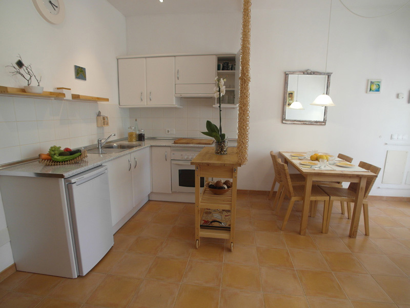Weiße Küche mit braun gefliestem Boden und einer weißen Küchenzeile