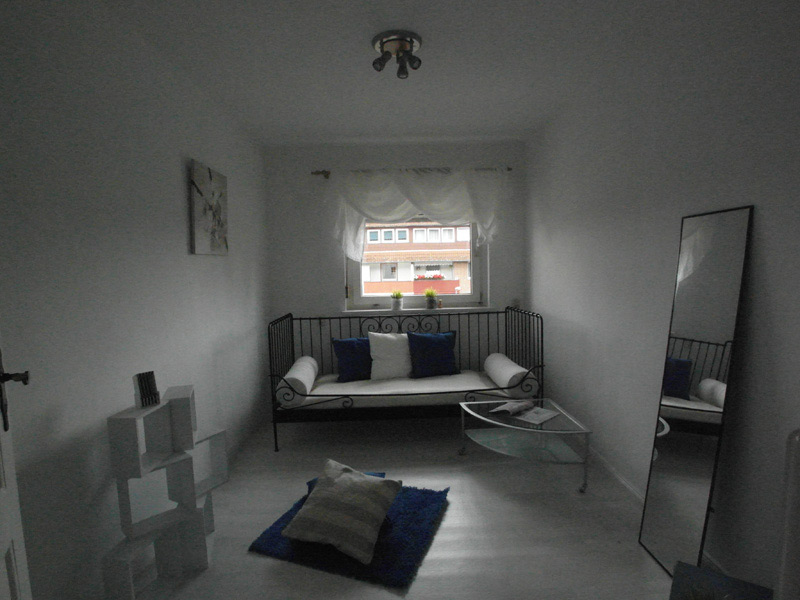 Zimmer mit einem Bett mit Metallrahmen einem großen Spiegel und einem Würfelregal