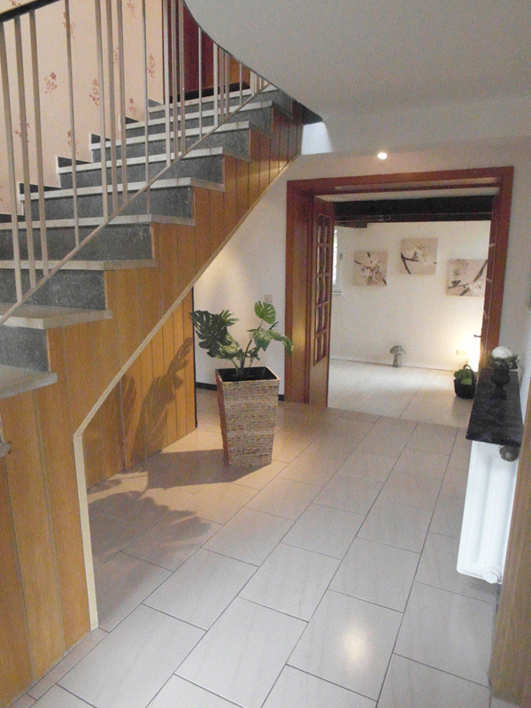 Treppenhaus mit einer Holz-Doppeltür und einem weiß gefliesten Boden