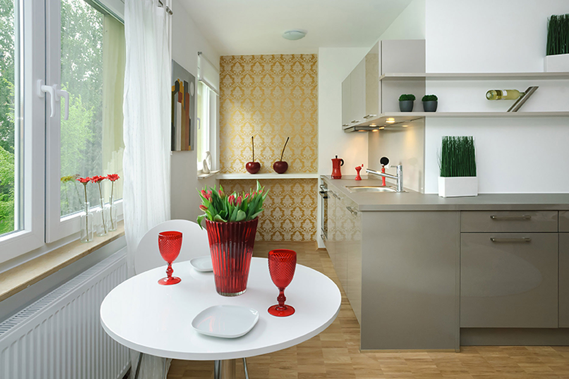 Weiße Küche mit Laminatboden, einer grauen Küchenzeile und einer gold-weißen, floralen Tapete