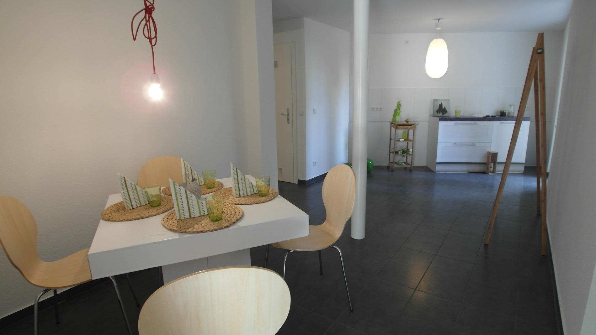 Weißes, offenes Esszimmer mit schwarz gefliestem Boden und einer weißen, schmalen Säule