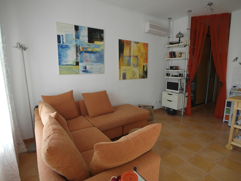 Weißes Wohnzimmer mit rot-braunen Bodenfliesen und einer Tonfarbenen Eckcouch