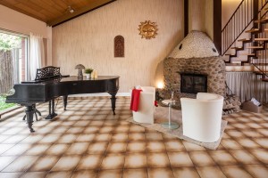 Rustikales Wohnzimmer mit einem Piano und einem massiven Ofen aus Naturstein