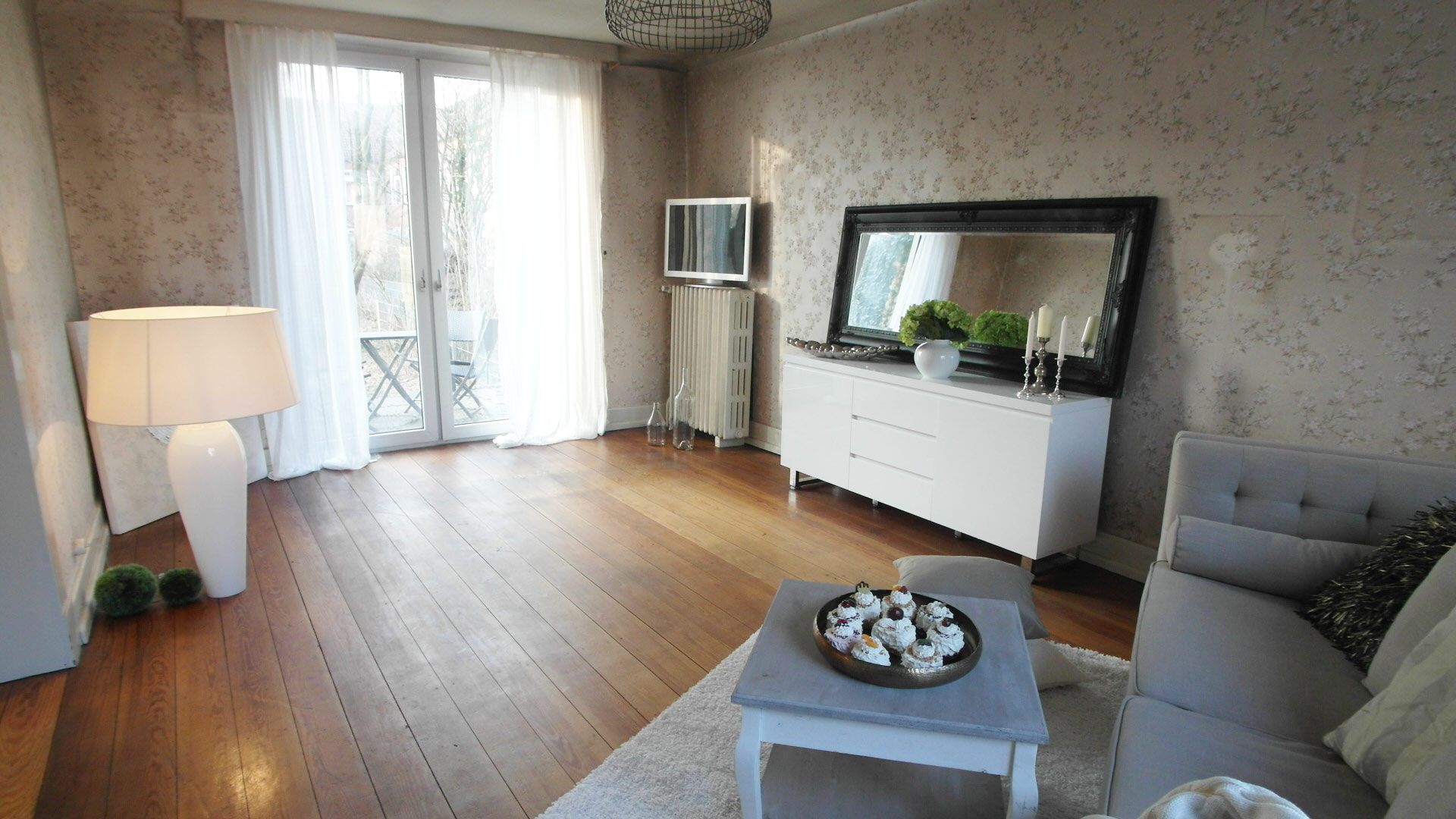Wohnzimmer mit beiger, floraler Tapete und einem Echtholzboden